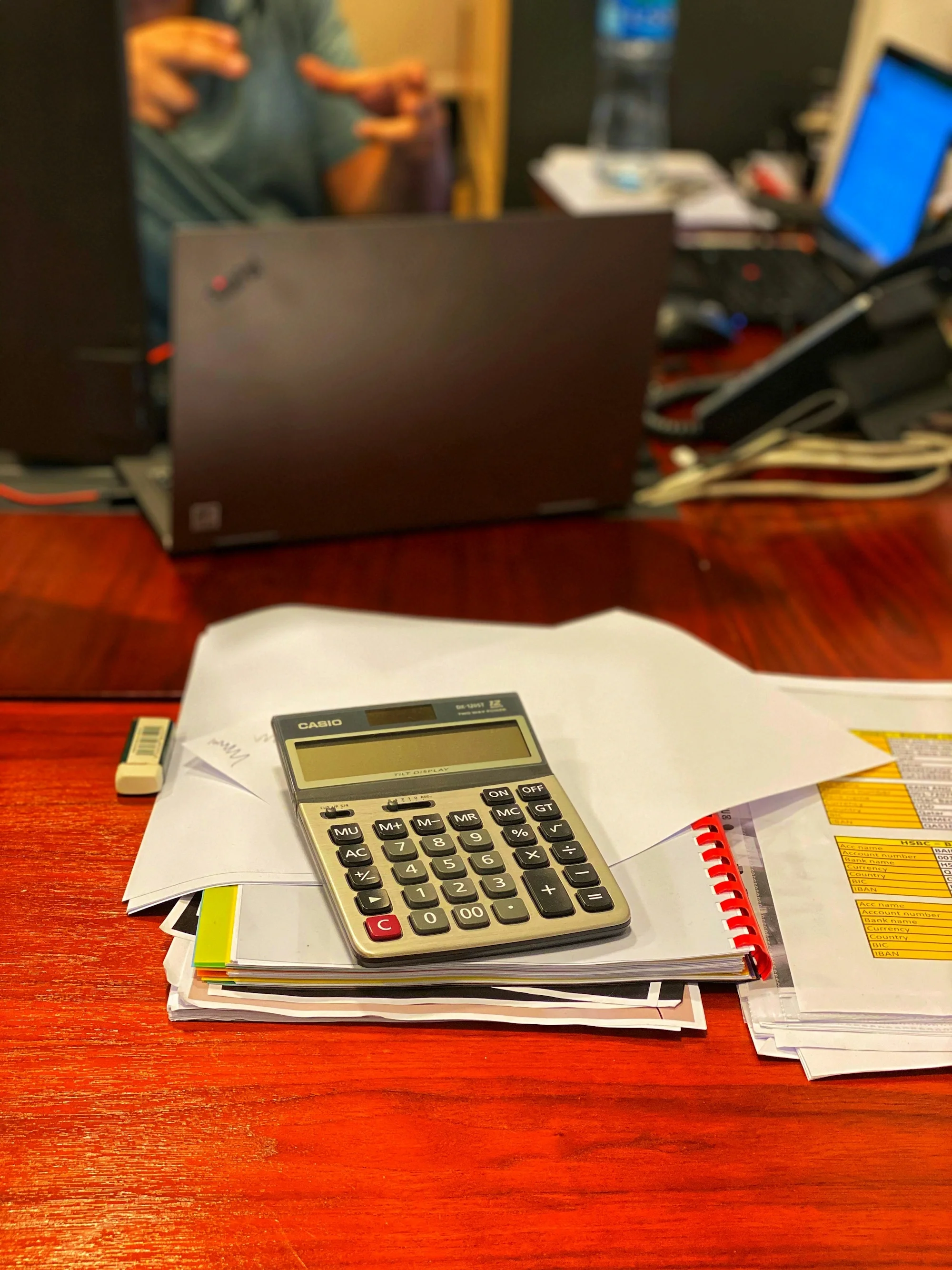 Calculadora sobre un montón de papeles en una mesa de despacho