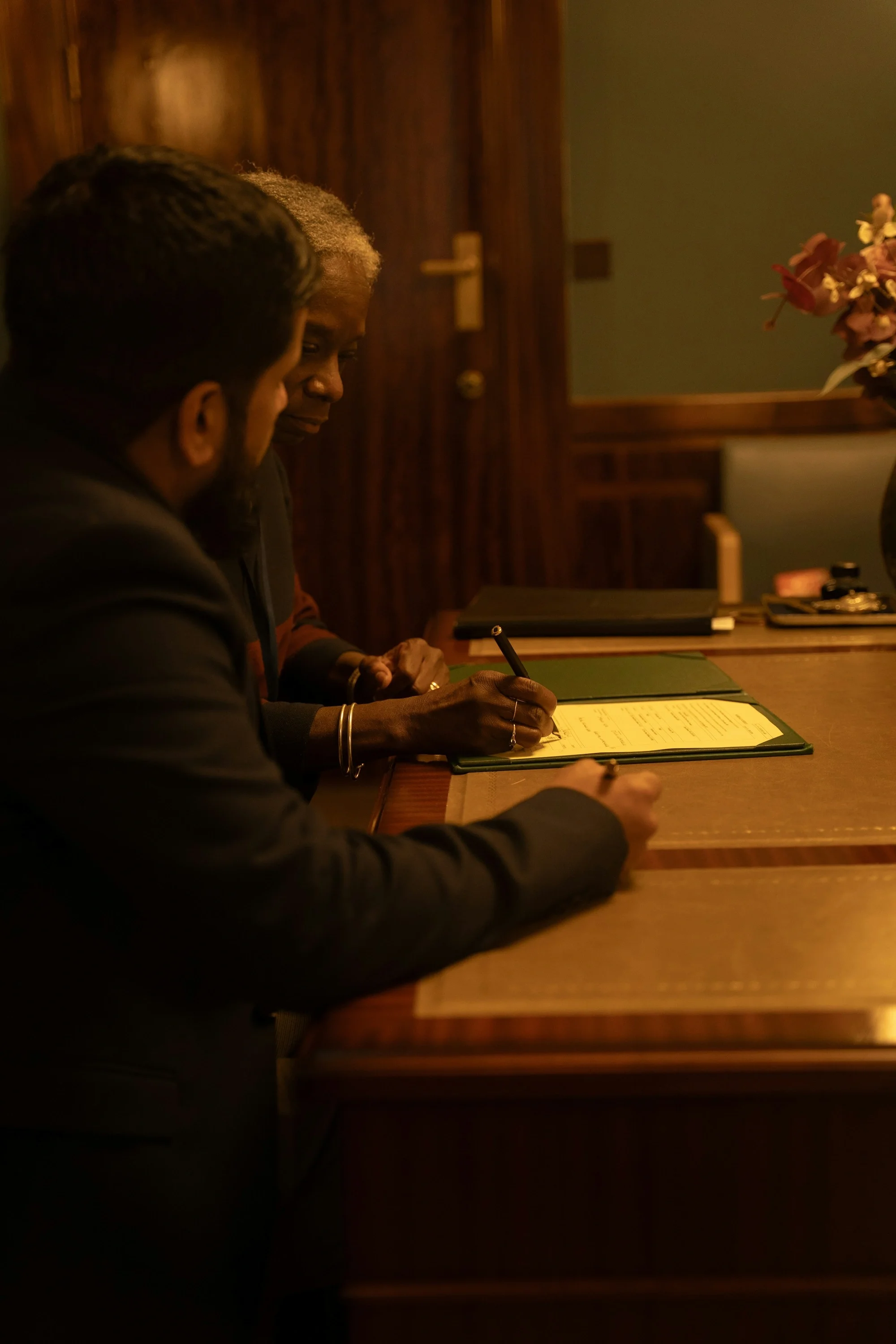Dos personas firmando una escritura en un despacho